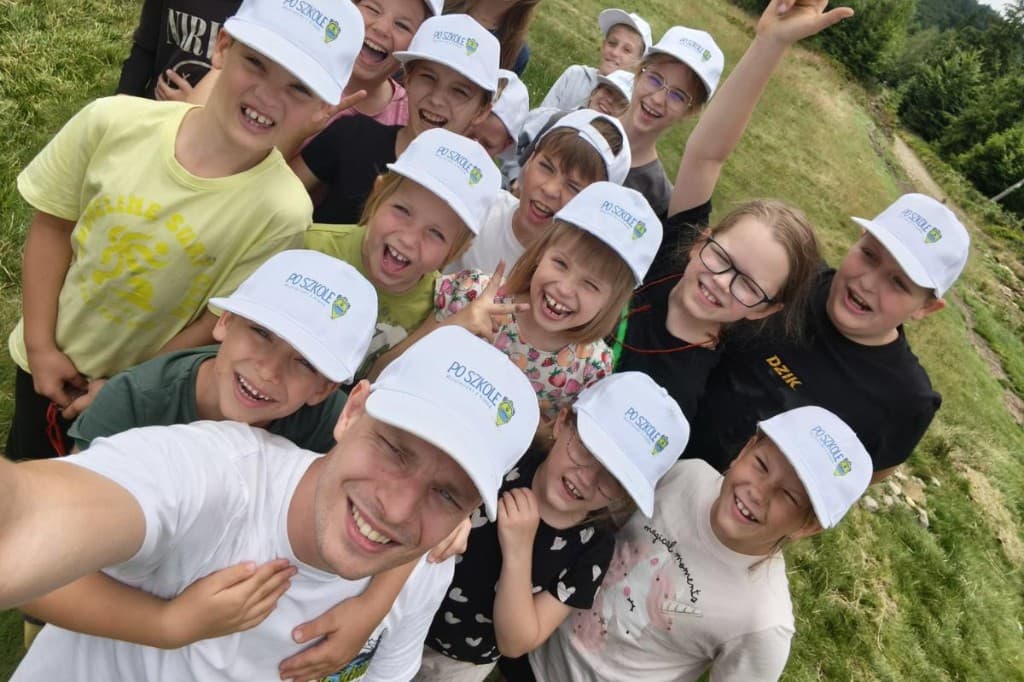 Uśmiechnięta grupa w czapkach Po Szkole na wycieczce